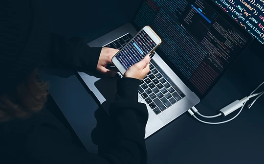 Image of someone using laptop and searching on phone